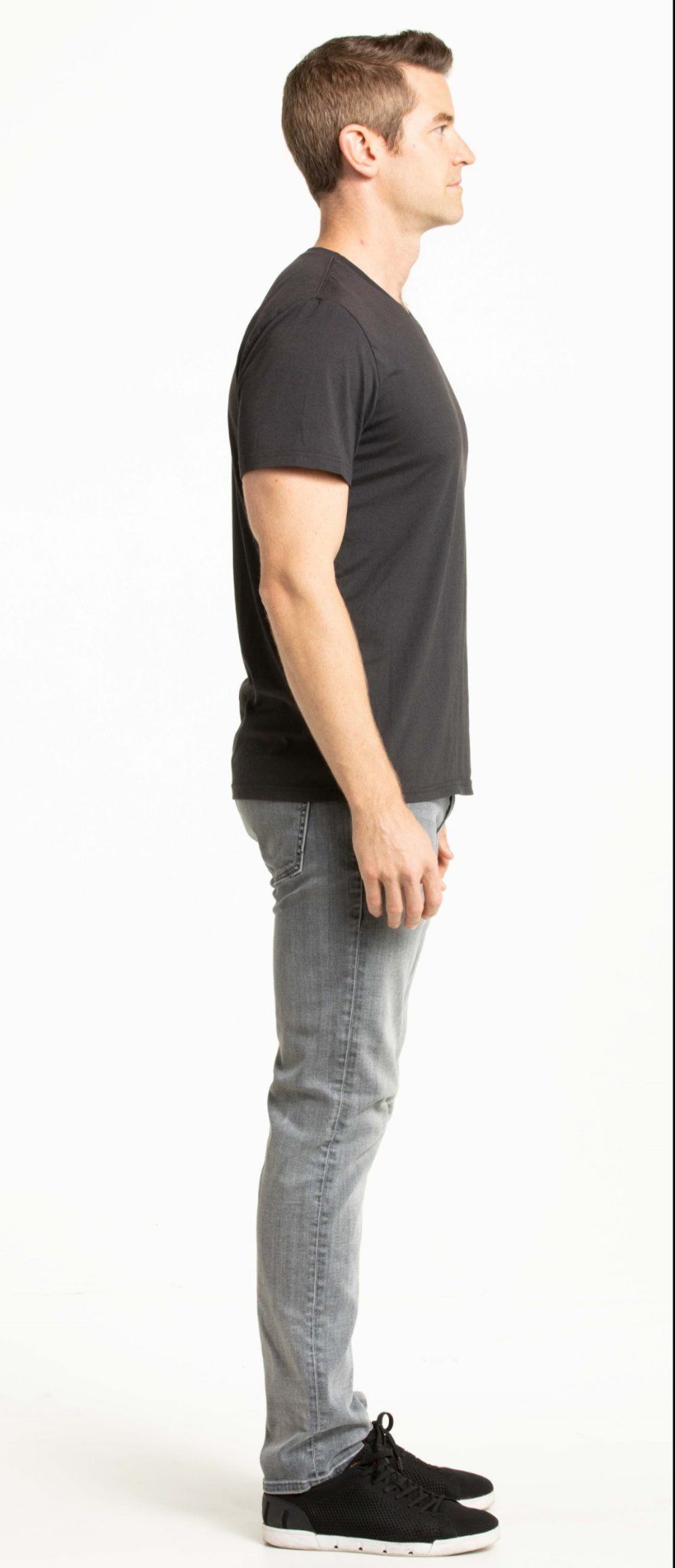 Side profile of male fit model Joe Cummings in a black tee and jeans, current studio photo