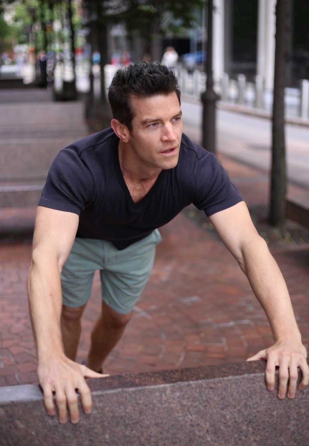 Male fit model Joe Cummings outdoors in a dark tee and shorts, current casual photo